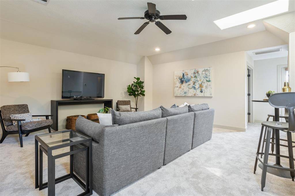 The third-floor entertainment space offers the perfect setting for movie nights, game days, or casual lounging—complete with plush carpeting, skylight illumination, and direct access to the adjacent wet bar for effortless hosting.
