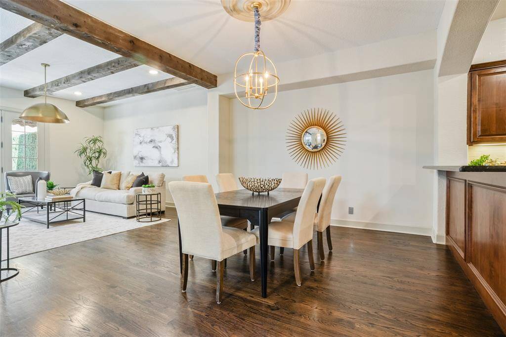 From this view, the dining room reveals its effortless connection to both the living area and kitchen—perfect for hosting with grace and ease. Rich hardwood floors, rustic ceiling beams, and ambient lighting set the stage for evenings filled with laughter, warmth, and memorable moments.