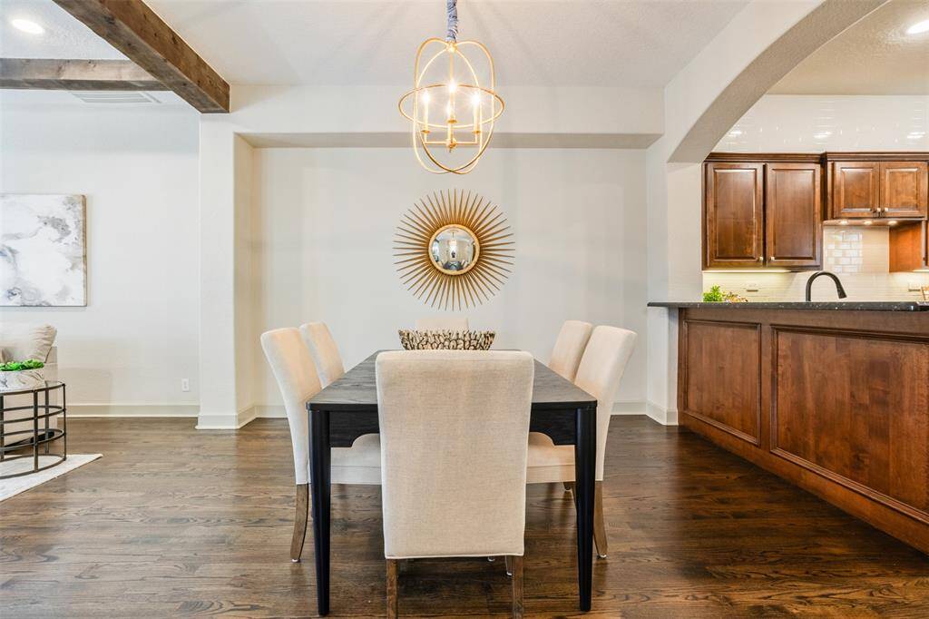 This inviting dining space pairs beautifully with the warmth of the adjacent kitchen, creating an ideal setting for both quiet dinners and festive gatherings. With rich wood cabinetry, a serving bar, and seamless flow into the living room, every detail is designed to bring people together.