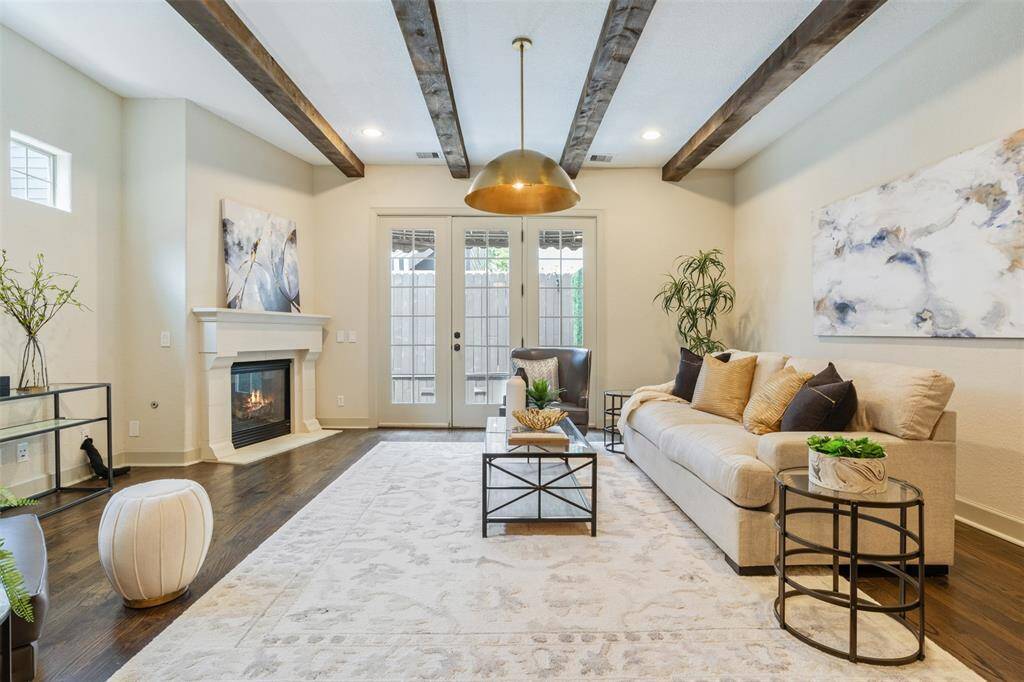 Framed by rustic beams and anchored by a glowing fireplace, this living room captures the essence of comfort and connection. Whether you’re curled up with a good book or entertaining guests, the seamless flow from dining to patio invites effortless living in every season.