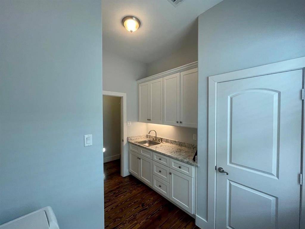Dedicated laundry space with granite countertops, deep stainless-steel utility sink, and abundant upper and lower cabinetry—ideal for organization and functionality.
