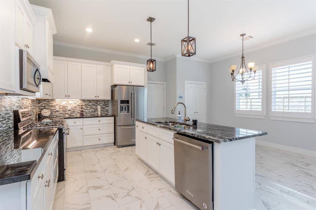 The garage opens to the kitchen and dining area. Top grade appliances, custom lighting, and ample cabinetry. There is a two-door pantry along the dining area wall.