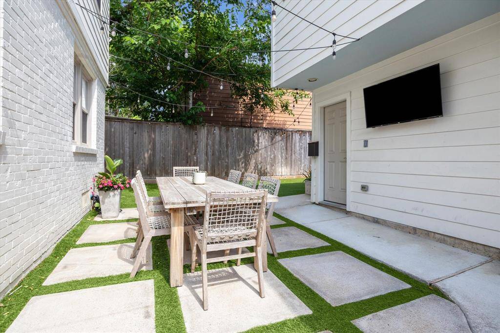 Turfed and landscaped outdoor dining space complete with mosquito misting system, tv and twinkle lights.