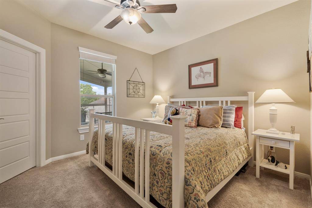 Cozy bedroom with soft carpet, overlooks the balcony window providing natural light and a view.