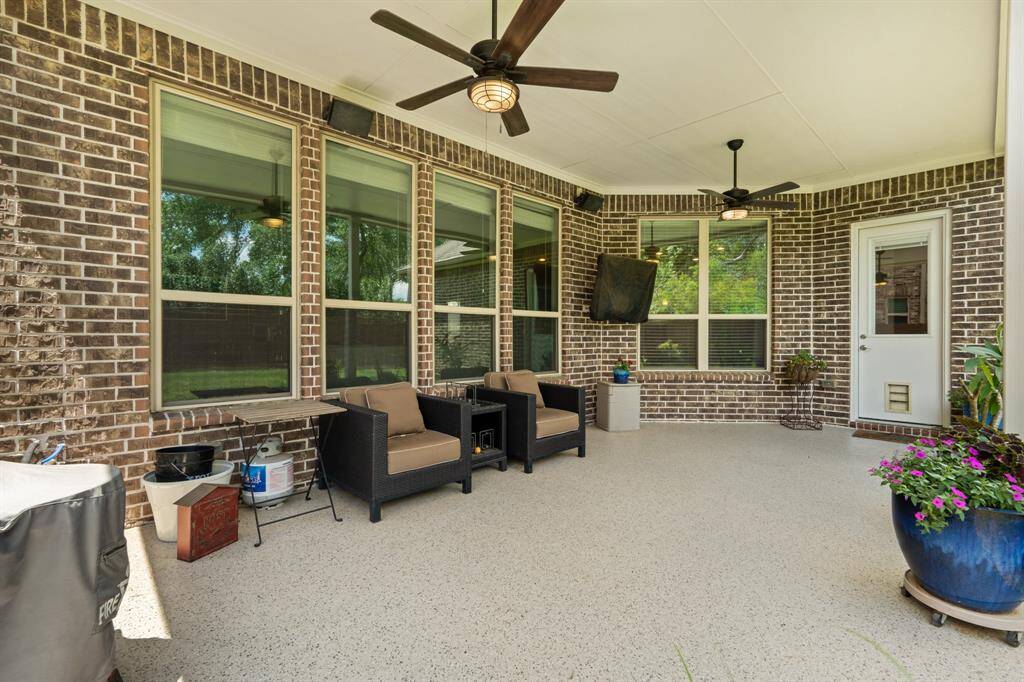 This inviting spacious covered patio features stylish brick walls, large windows, ceiling fans ideal for outdoor entertainment. Added Polyurea coating to the concrete floor, extra half glass door with in-frame blinds at patio passenger entry and hot/cold water, gas stub lines for an Outdoor Kitchen. *TV excluded.