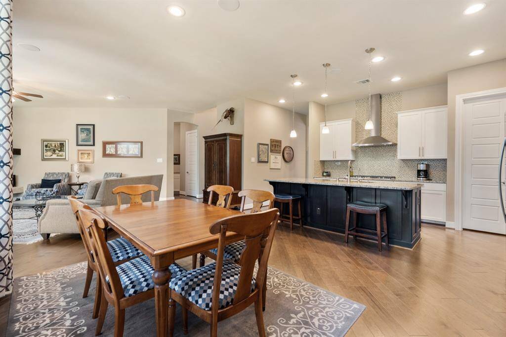 This open-concept living space features a modern kitchen with a large island, pendant lighting, and stainless steel appliances. Adjacent is a cozy breakfast area with ample natural light, flowing seamlessly into a comfortable living room.