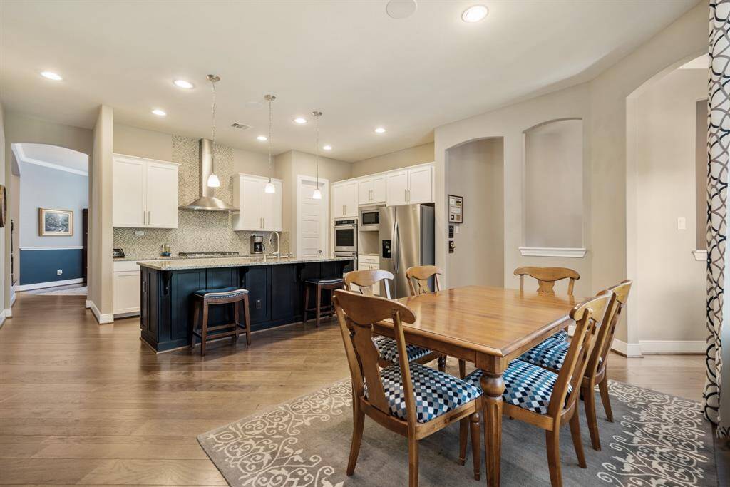 This photo showcases a spacious, open-concept kitchen and dining area. The kitchen features modern stainless steel appliances, a large island with bar seating, and stylish pendant lighting. The dining area is well-lit with recessed lighting. The space is inviting and functional for gatherings.