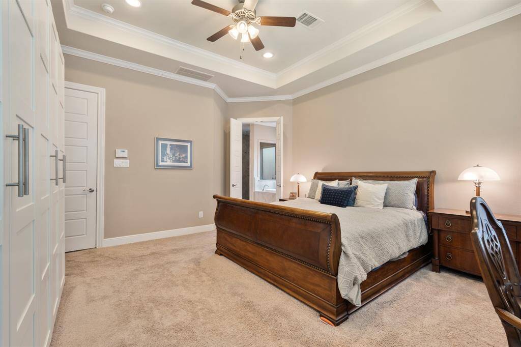 This primary bedroom features a spacious layout with neutral walls and upgrade carpet pad, and tray ceiling. It includes a large walk-in closet, additional Custom Elfa Closet system.En-suite bathroom with upgraded primary bathroom shower to oversized SPA unit with overhead rain shower system, handheld wall shower head, and 3 wall spa jets.