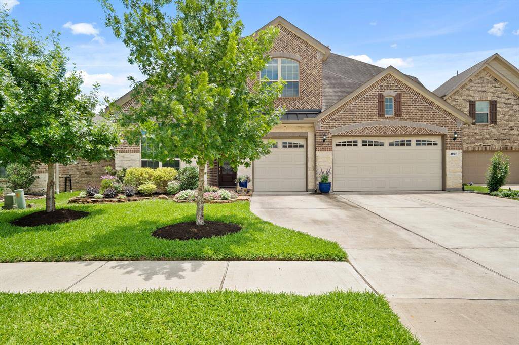 This photo shows a charming two-story brick home with a well-maintained front yard. It features a spacious three-car garage and beautifully landscaped surroundings, offering excellent curb appeal in a serene residential neighborhood. Added 4" seamless gutters to perimeter of house.