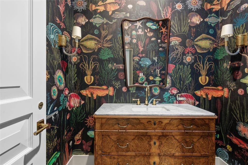 Powder Bath (West) Antique burled walnut vanity with marble top and Watermark unlacquered brass fixtures, wall mirror, select wallpaper, pair of single-light wall sconces and separate glazed paneled water closet