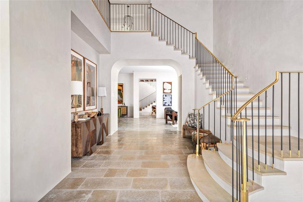 The elegant custom designed and site built grand front staircase with brass railing and limestone treads as well as state of the art lighting