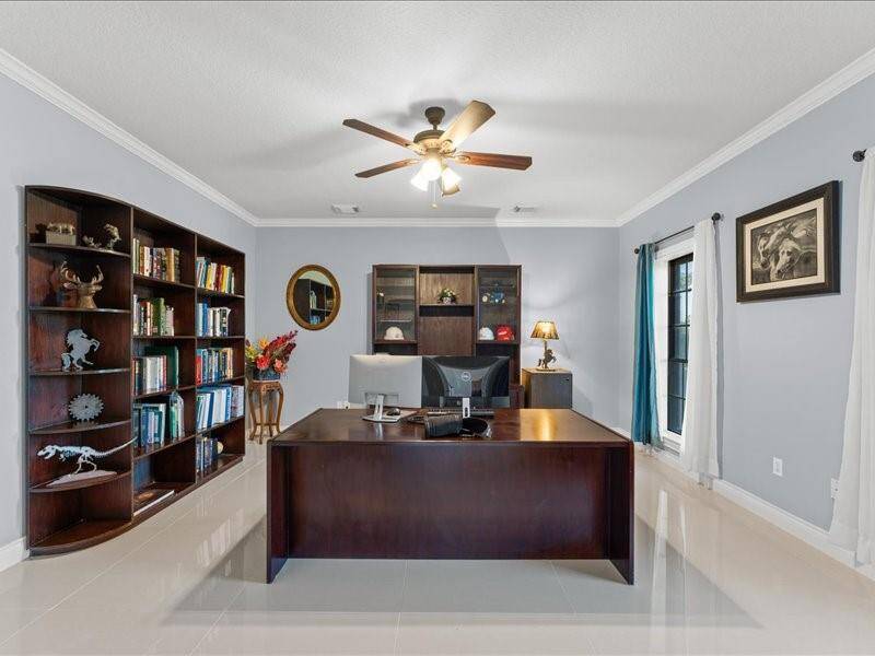 Spacious home office with ceiling fan, and ample natural light from the windows, creating a bright and professional workspace.