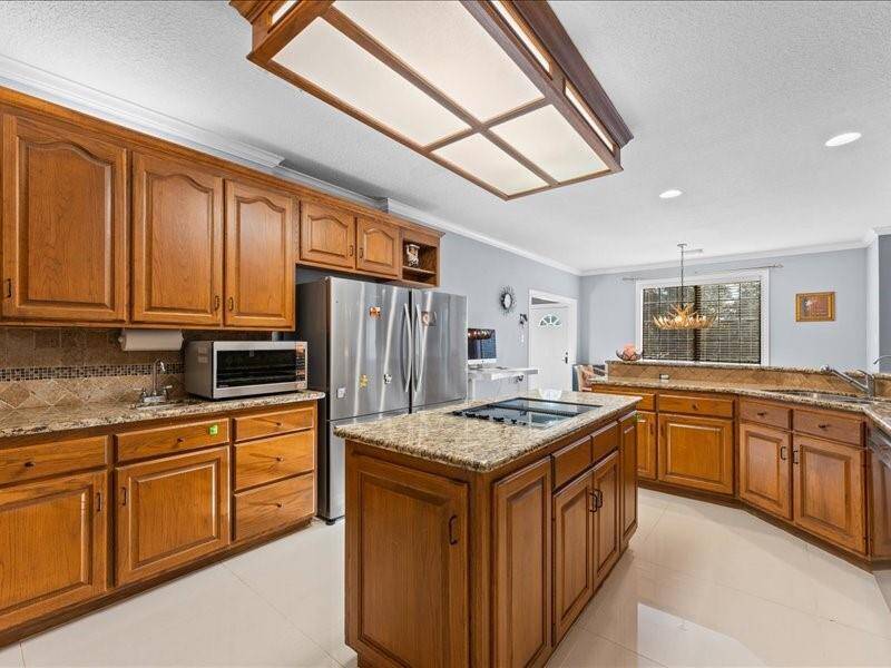 The large island in the klitchen provides additional workspace and storage, while the recessed lighting and light gray walls create a functional and inviting cooking area.