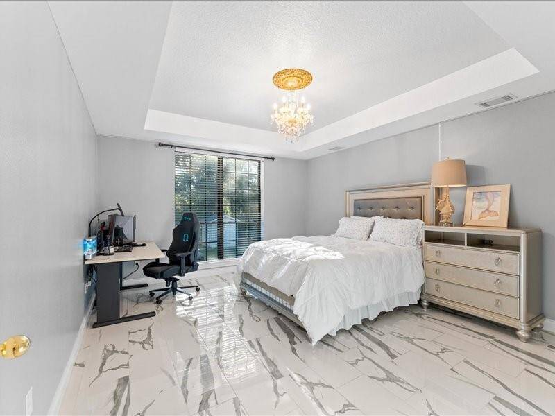 The downstairs bedroom with elegant with marble-like floor, and tray ceiling.