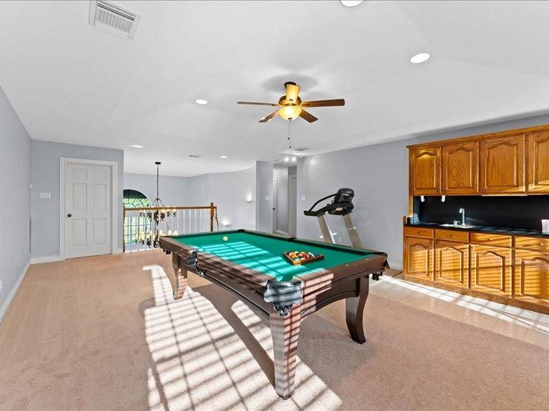 The game room features a wet bar with wooden cabinetry, ideal for entertainment.