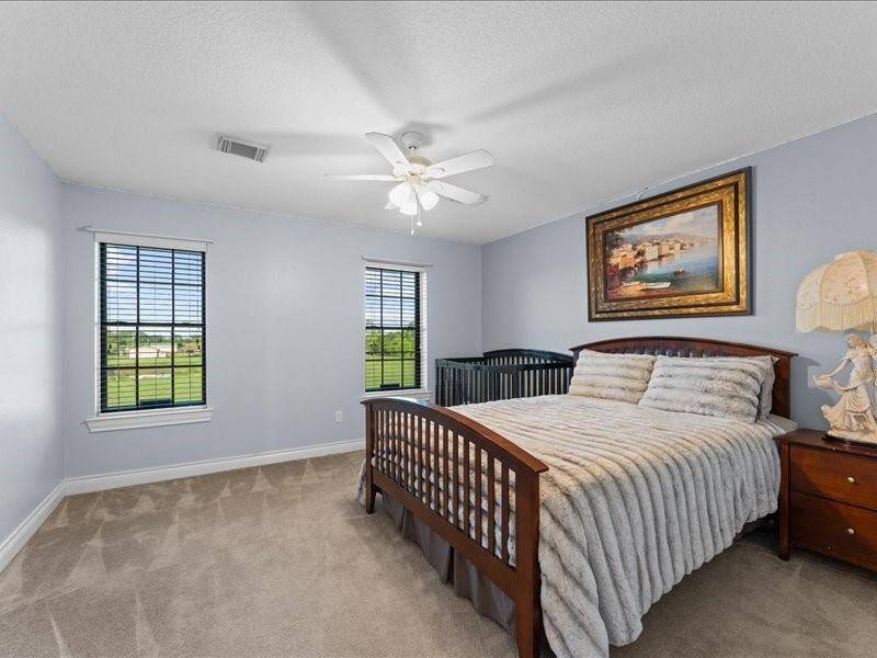Bedroom #3 features soft blue walls, a ceiling fan, and two large windows that allow natural light.