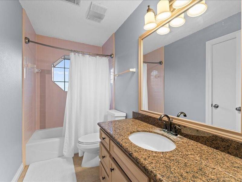 The second bathroom features a granite countertop with an under-mount sink, a large mirror, and warm lighting.