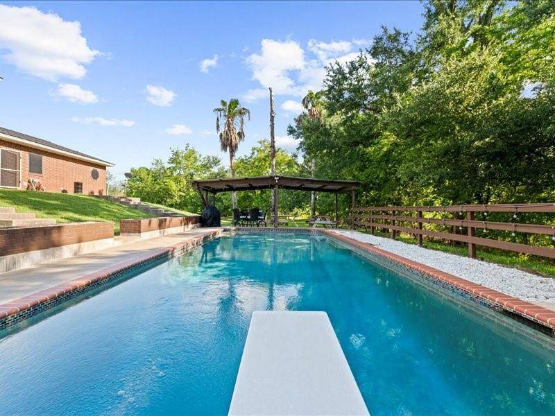 The gunite in-ground pool features a diving board.