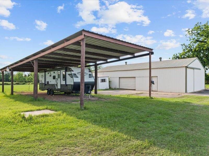 The large metal carport, perfect for RV storage, and a sizeable metal building or workshop, offers ample storage or workspace.
