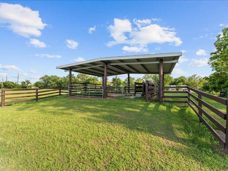 The fenced area with a covered structure, ideal for livestock or outdoor storage.