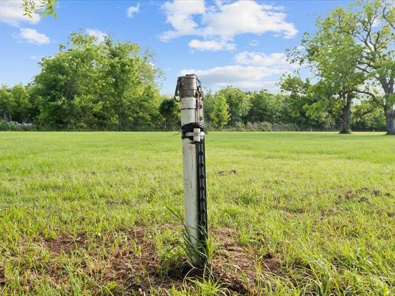 The irrigation wellheads in a grassy yard surrounded by trees.