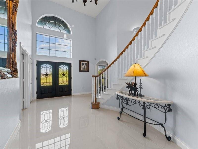 Elegant foyer features a grand, spiral staircase, lofty ceilings, and abundant natural light from large windows.