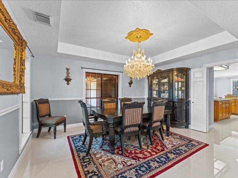 Elegant dining room featuring a chandelier, ornate mirror, and an open doorway leading to the kitchen.