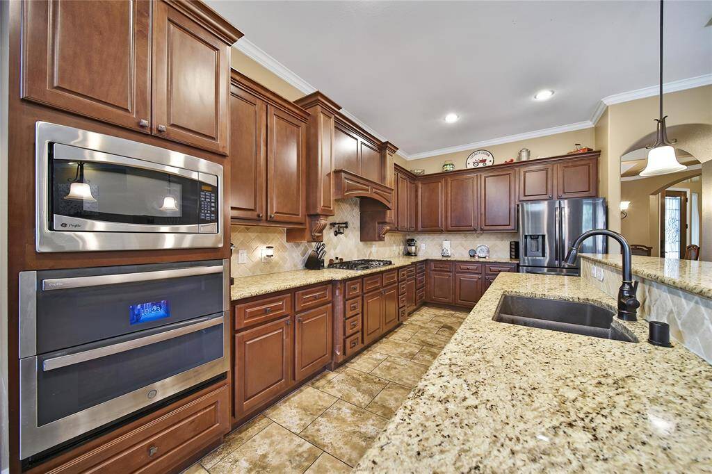 Kitchen includes a recent GE Profile double oven, pot filler, gas cooktop, upgraded cabinets, granite, breakfast bar and oversized pantry.