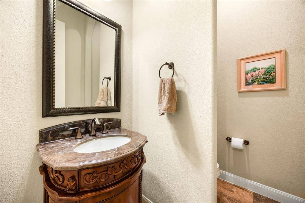A convenient half-bath featuring a sleek pedestal sink and elegant framed mirror, offering a stylish and functional space for guests.