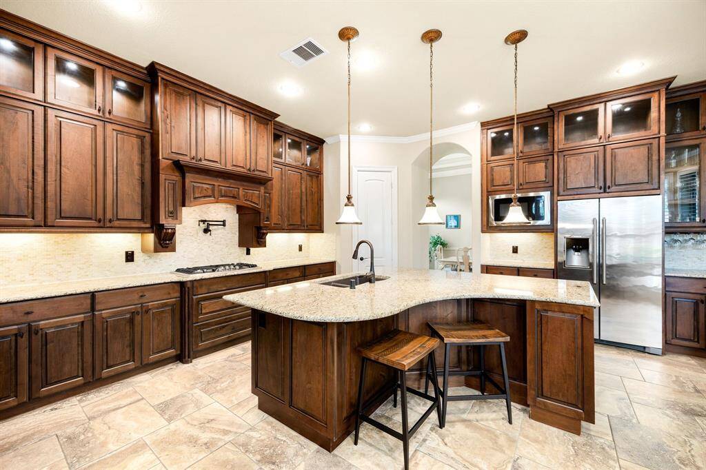This kitchen is by far any chef’s dream! This spacious kitchen features large windows, high ceilings, dark stained wood cabinets, granite countertops, SS appliances, modern tile backsplash, recessed lighting with additional custom pendant lighting, extended counter space, granite kitchen island with double sink and space for breakfast bar and a walk-in pantry all overlooking your huge family room.