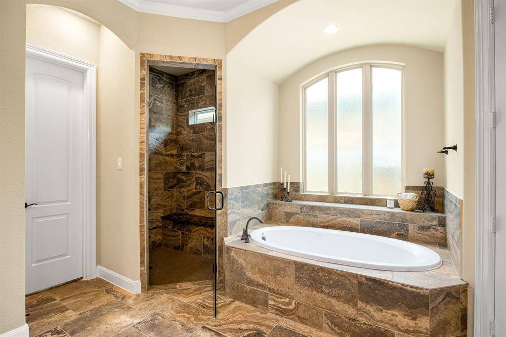 This additional view of the primary bath showcases a walk-in shower with tile surround and a separate garden tub perfect for soaking after a long day.