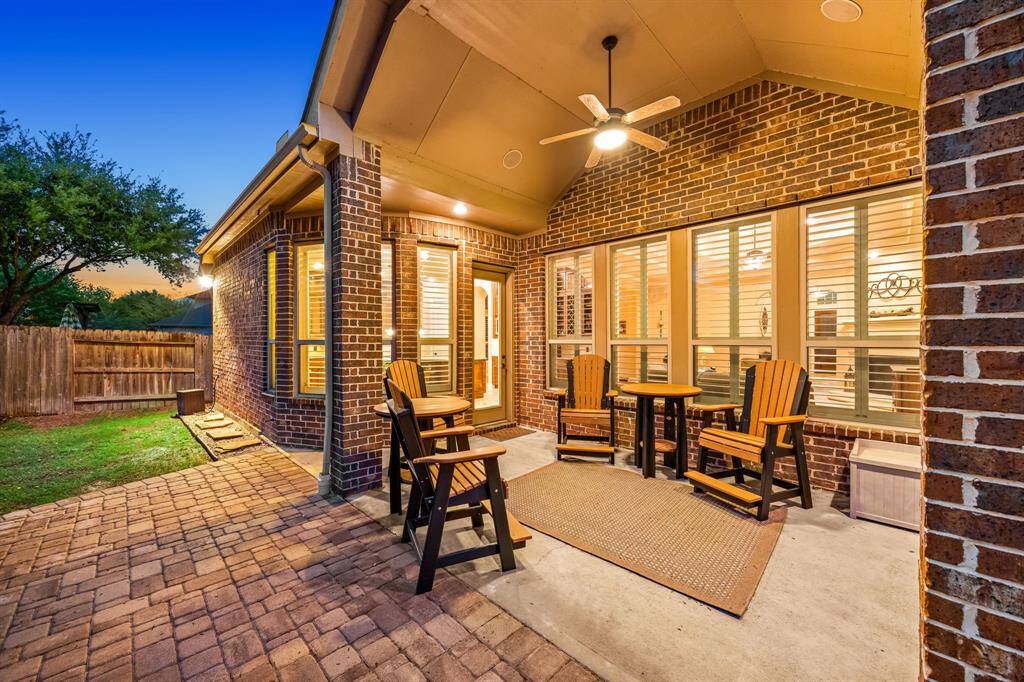 Enjoy evening breezes under this covered patio, complete with a ceiling fan and ample seating space, perfect for relaxed outdoor living.