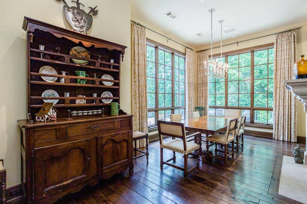 Spacious Breakfast Room with plenty light. Windows overlook the pool and side yard.  Hardwood floors. Double-sided stone fireplace separates Breakfast room from Family room.