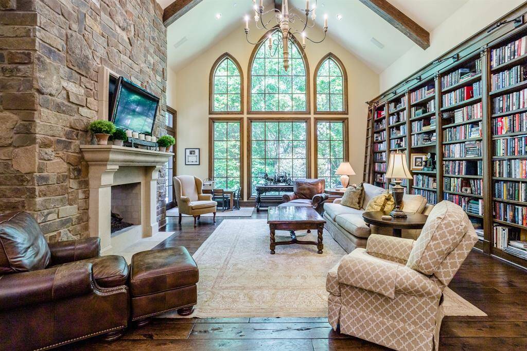 Family room with white oak hardwood floors. Custom designed & built bookshelves. Two-sided gas and wood burning Stone fireplace separating Family room from Breakfast room.  Huge windows showcase secluded setting with lush trees.  Tons of light.  Arched ceiling with wood beams accent this gorgeous room.