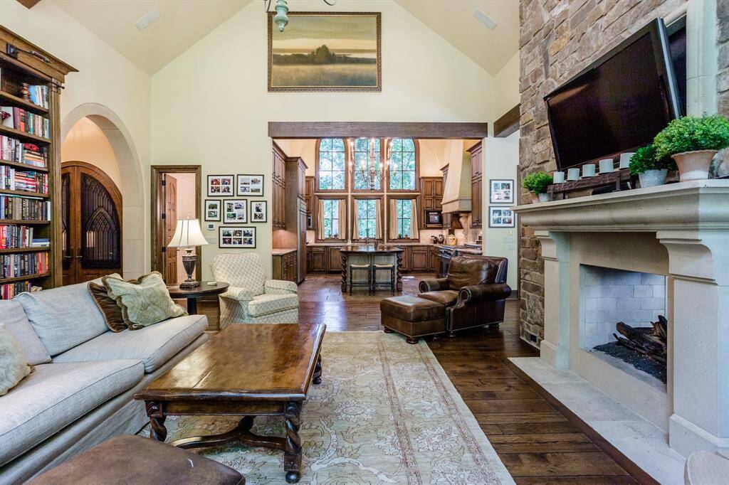 Family room with white oak hardwood floors. Custom designed & built bookshelves. Two-sided gas and wood burning Stone fireplace separating Family room from Breakfast room.  Huge windows showcase secluded setting with lush trees.  Tons of light.  Arched ceiling with wood beams accent this gorgeous room.