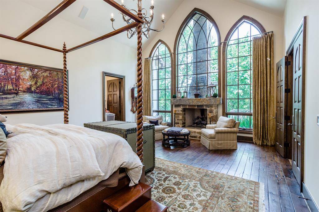 Stunning Primary Bedroom. First floor. Discreetly tucked away down a private hallway at the back of the home.  White Oak hardwood floors. Arched ceiling. Sitting area in bedroom flanking stone fireplace.