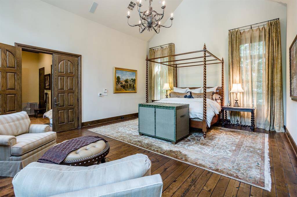 Primary Bedroom. First floor. Discreetly tucked away down a private hallway at the back of the home.  White Oak hardwood floors. Arched ceiling. Sitting area in bedroom flanking stone fireplace.