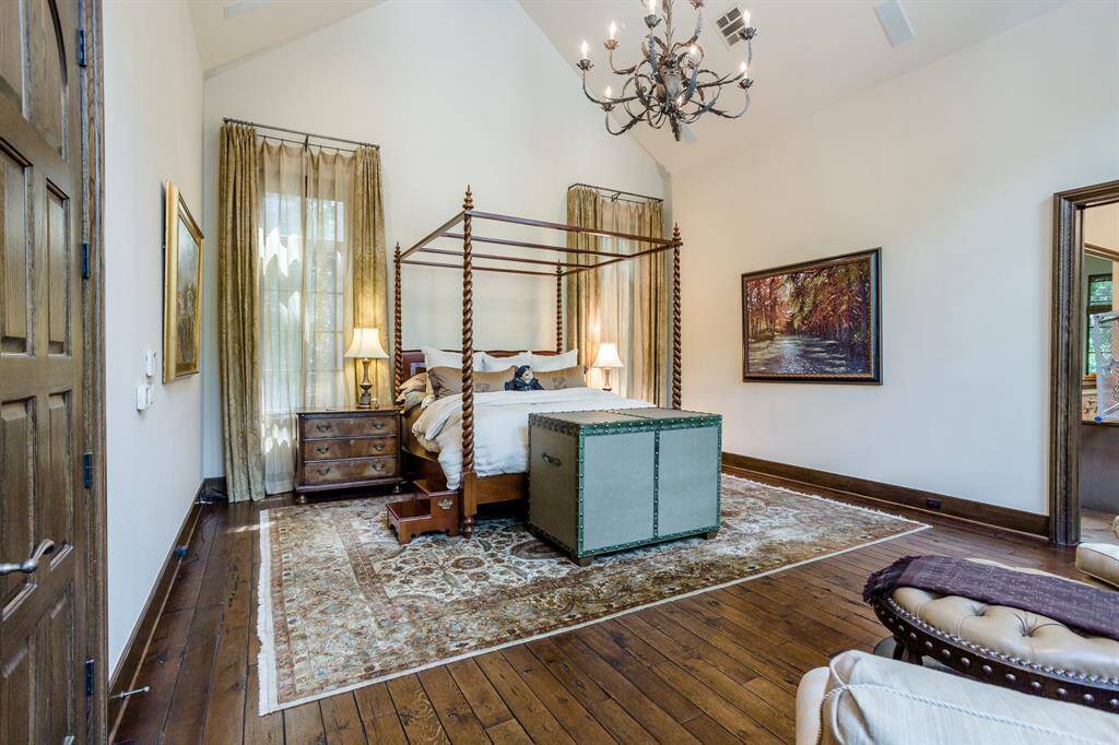Another view of the Primary bedroom.  Primary Bedroom. First floor. Discreetly tucked away down a private hallway at the back of the home.  White Oak hardwood floors. Arched ceiling. Sitting area in bedroom flanking stone fireplace.
