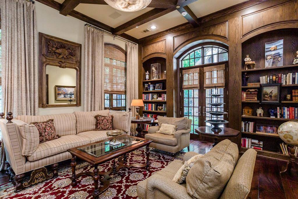 Living Room with mahogany hardwood floors and access to side courtyard. Custom built cabinetry and ceiling beams.