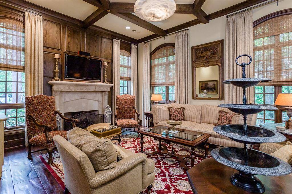 Living room with stone surround fireplace, mahogany hardwood floors, ceiling beams.