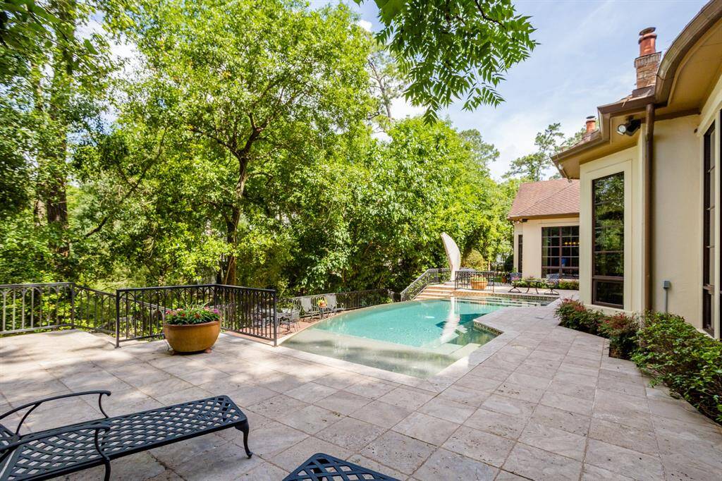 Custom designed negative edge pool with falls down to lower level deck.  Pool looks into tree tops high above Buffalo Bayou.