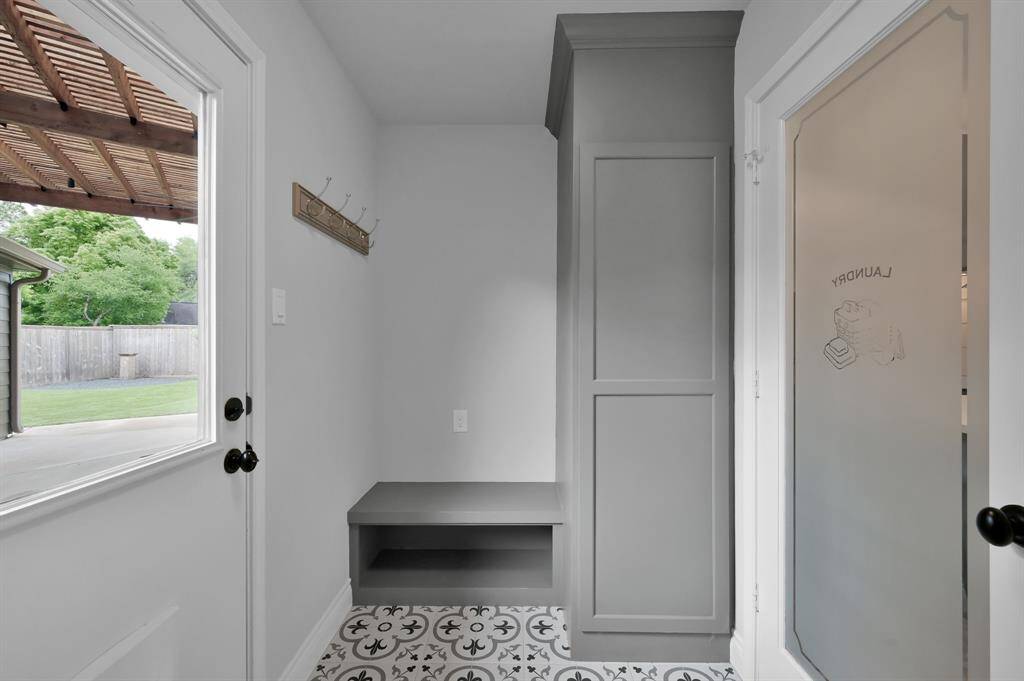 Spacious laundry room with custom tile flooring and access to the back yard.