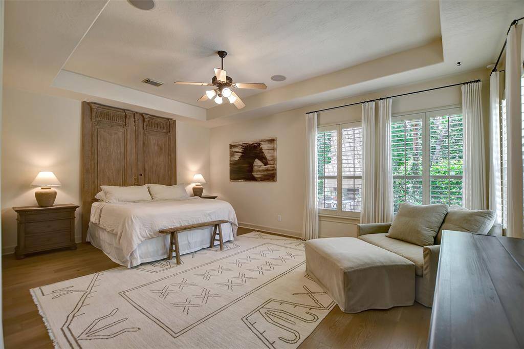 Spacious and serene primary bedroom featuring large windows with beautiful views of the backyard oasis.