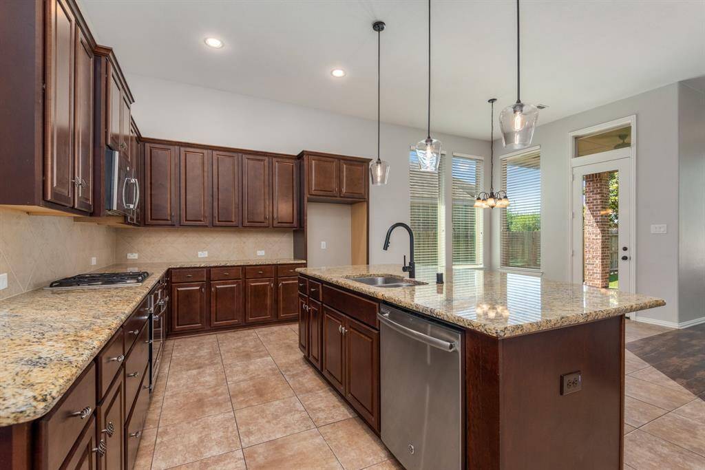 This island kitchen is huge. Tons of cabinets and counter space, pretty pendant lights, built in desk, walk in pantry and bar seating.