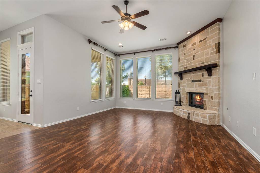 Sun-drenched family room with walls of windows and floor to ceiling stone fireplace.