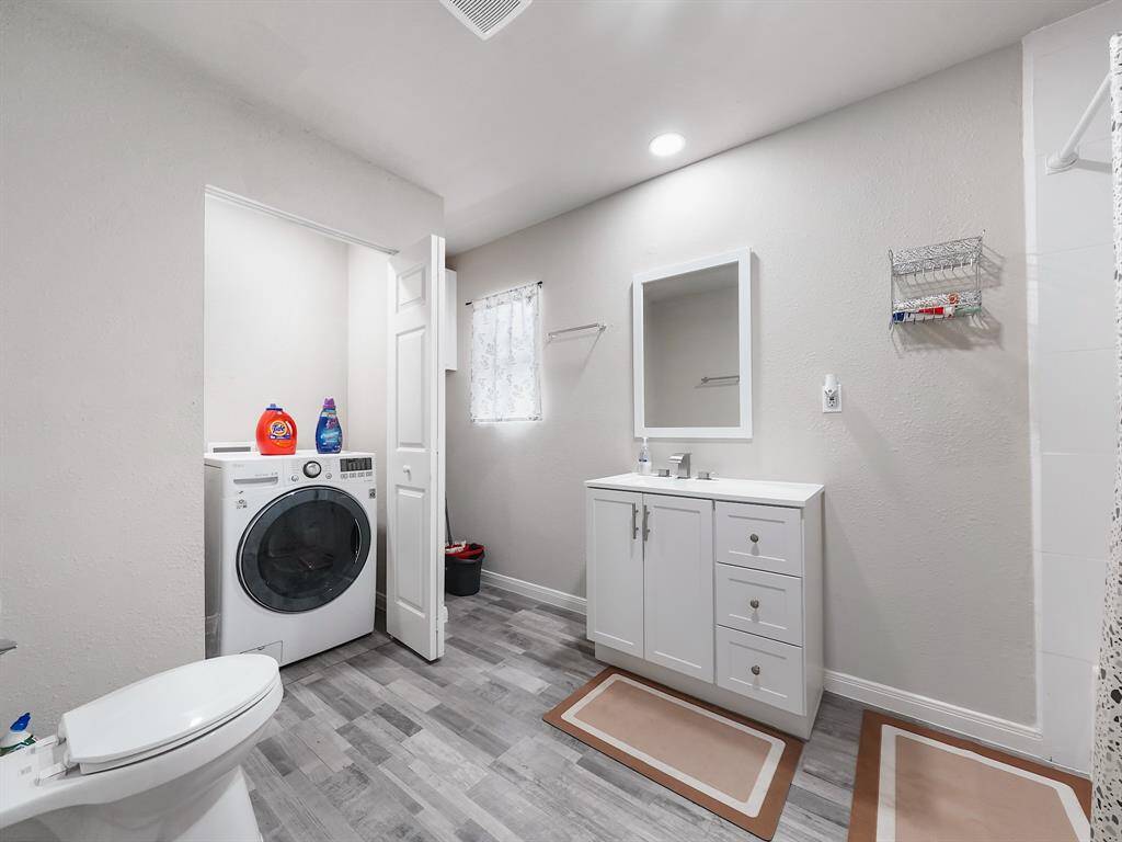 The second full bathroom offers crisp finishes, a clean vanity, and an integrated laundry area—combining convenience and efficient use of space in a stylish setup.
