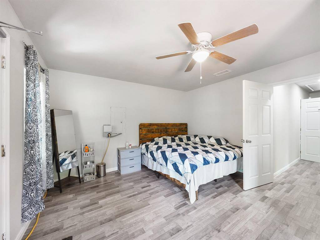 A spacious bedroom with a comfortable bed, durable vinyl flooring, ceiling fan, and large window—this room is both stylish and functional, perfect for restful nights or active days.