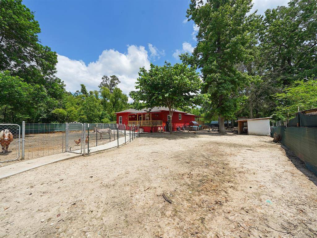 A picturesque view of the home from a distance reveals the long walkway lined by enclosures—ideal for livestock or poultry—highlighting the peaceful setting and welcoming approach.