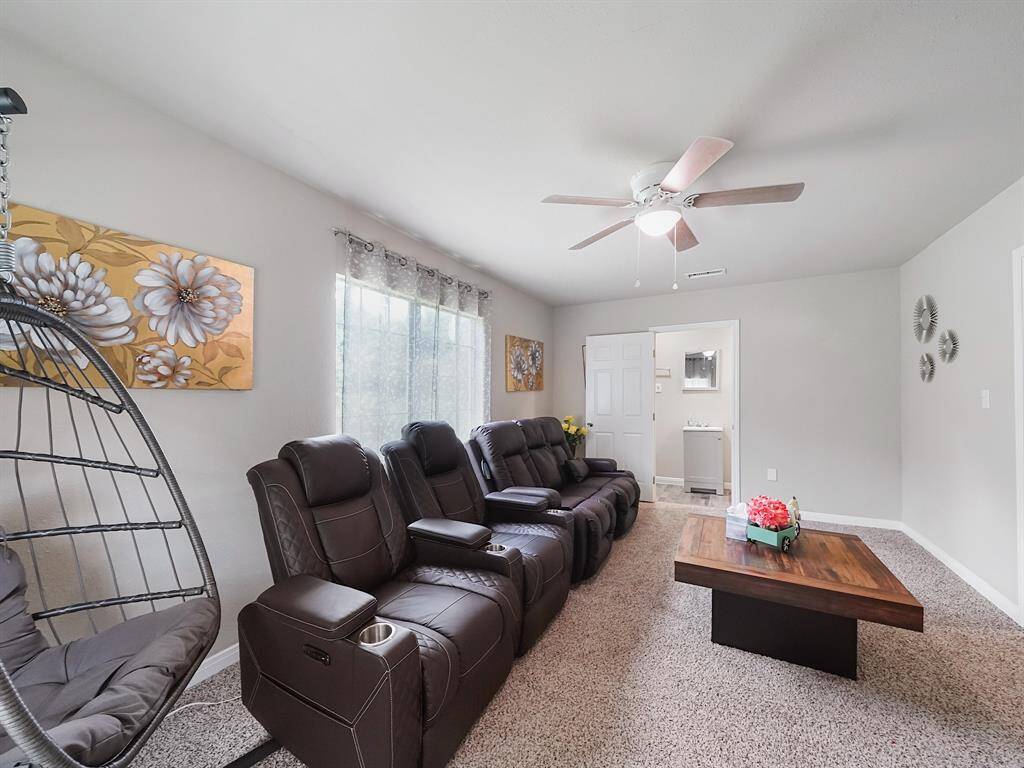 This versatile carpeted room comes fully furnished and could serve as a private lounge or bedroom. A large window, ceiling fan, and direct access to a bathroom enhance the comfort.