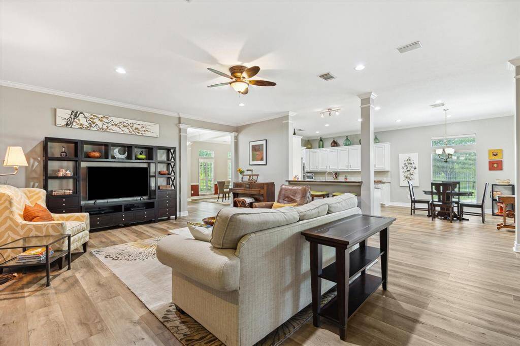 We are standing near the bookshelves and the primary suite, looking toward the breakfast room, kitchen and formal dining room.